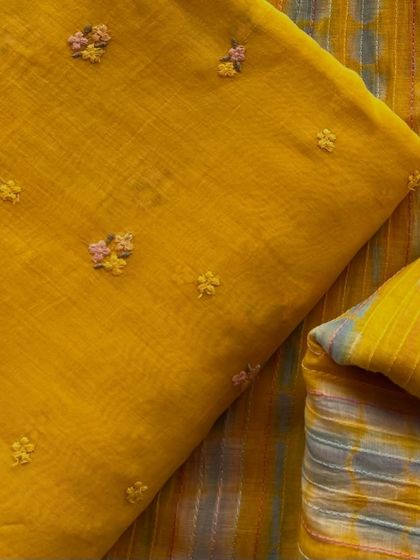 A beautiful set of Mul Chanderi fabrics in mustard yellow, one with delicate floral embroidery and the other with a complementary striped pattern.