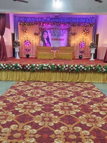 A stage setup for a formal event, which can also be adapted for a reception or engagement. The clean backdrop with a personalized banner and floral arrangements looks professional and celebratory.