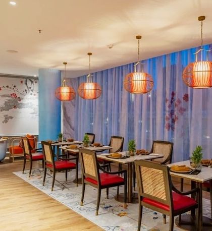 In this section of the Oriental Pavilion, a hand-painted mural of a traditional landscape complements the sheer blue curtains and birdcage-style lanterns. The design creates a serene and intimate dining nook.