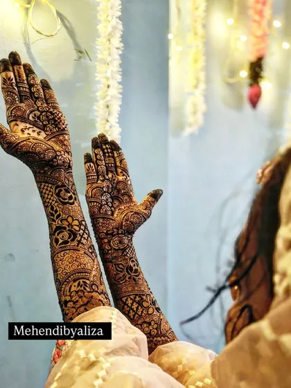 A classic bridal pose showing off the full length of the intricate mehendi design. The rich patterns cover the hands and arms completely for a traditional bridal look.