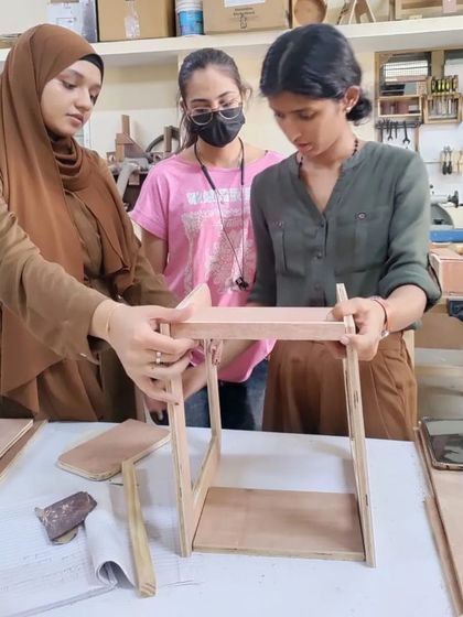 Students assembling a small piece of furniture. This hands-on experience is invaluable for understanding how designs translate into real-world objects.