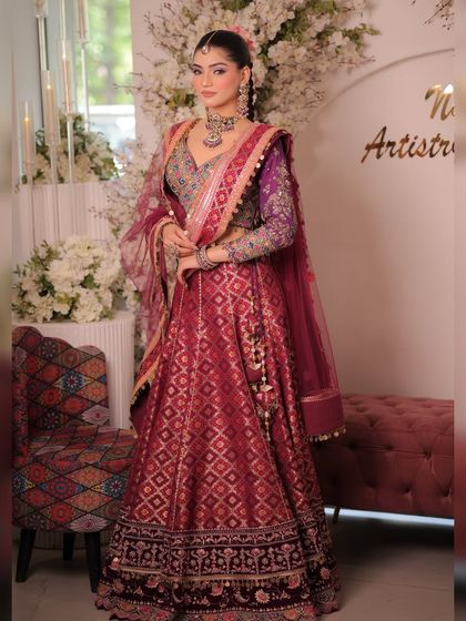 A beautiful shot of the model in the multi-colored silk lehenga, set against a floral backdrop. It highlights the festive and celebratory nature of the outfit.