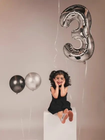 A classic, minimalist third birthday portrait. The focus is all on her adorable, surprised expression, making for a timeless memory.