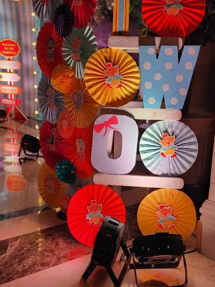 Colorful paper fan decorations and large letters spelling 'Woo Woo' at a carnival-themed event.