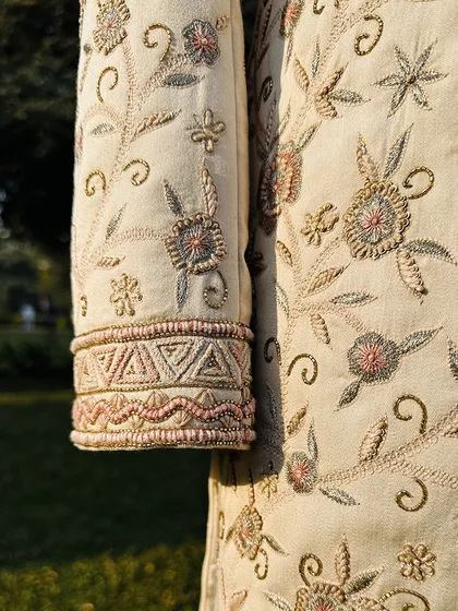 The sleeve detail of the Koyaliya Sherwani, showcasing the intricate floral motifs and geometric patterns on the cuff. This is the level of dedication we bring to every garment.