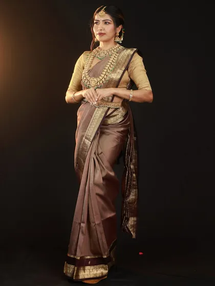 A full-length portrait to showcase the beautiful drape and fall of the brown silk saree. The side lighting adds depth and highlights the texture of the fabric.
