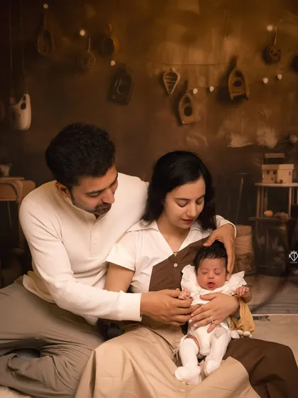 A wider angle of the new family, showing them seated together in the styled studio setting. This shot provides context and showcases the cozy, warm atmosphere of the session.