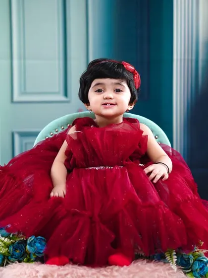 A bright smile from the birthday girl, seated in her little chair against a beautiful floral backdrop.