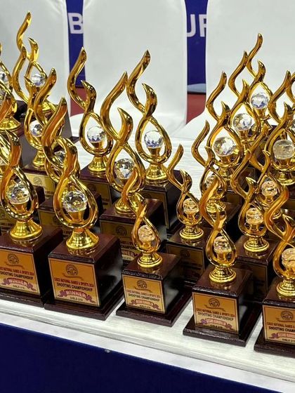 A close-up of the gleaming trophies prepared for the winners of the CISCE National Shooting Tournament, a symbol of their hard-earned victory.