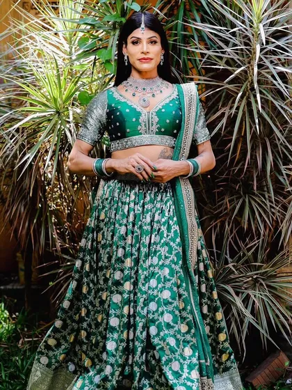 A full-length shot of the model in a green floral lehenga, adorned with our contemporary AD and emerald imitation jewellery set.