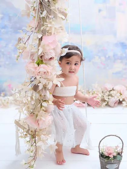 A toddler enjoys our floral swing set, designed with soft pastel colors. This bright and airy setup is perfect for capturing the innocence and curiosity of very young children.