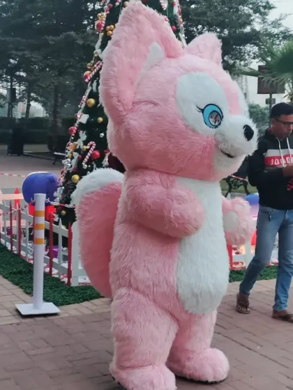 This adorable pink squirrel mascot adds a unique and cute touch to any celebration, seen here at an outdoor Christmas carnival.
