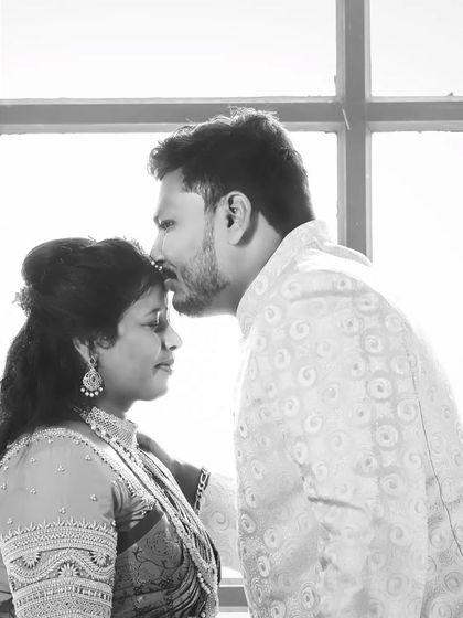 A tender moment captured in monochrome. The groom kisses the bride's forehead, a simple gesture of love that is made more powerful and timeless in black and white.