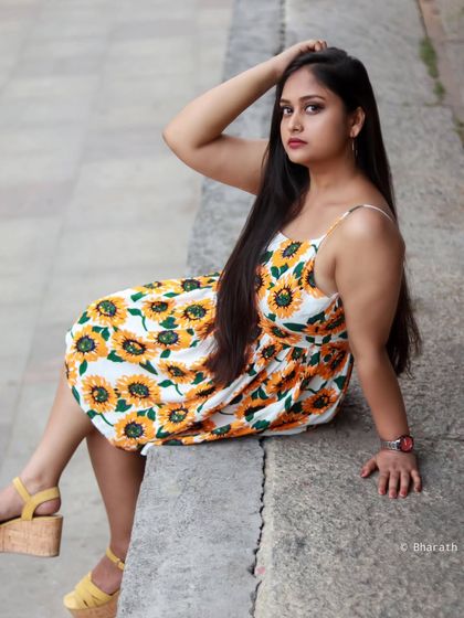 A casual, seated portrait on a city ledge. The sunflower dress brings a touch of summer to the urban environment.
