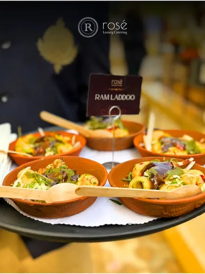 A server presents bowls of Ram Laddoo on a tray. This popular Delhi street food is elevated with our gourmet touch, offering a symphony of taste and luxury in every bite.