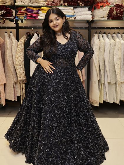 This full-length navy blue gown is a perfect example of an Indo-Western silhouette. The long sleeves and flowing skirt are covered in a delicate, shimmering leaf pattern, creating a glamorous look for an evening event.