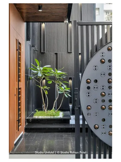 The entrance gate and wall feature custom metalwork with circular motifs, offering a hint of the detailed design language within.