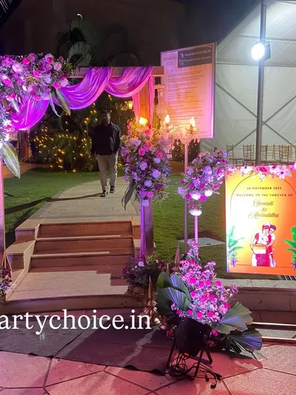 We designed this floral entrance arch for a reception, lit with purple uplighting to create a dramatic welcome for guests. The setup includes a personalized welcome sign with a fun caricature of the couple.