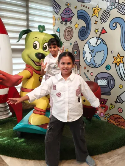 Two friends pose with our space-themed Tinga Dojo statue near the rocket ship.
