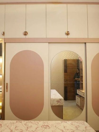 A beautiful kids' room with a soft pink theme, featuring a sliding wardrobe with a unique oval-mirrored door.
