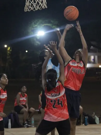 A player from the women's division goes up for a rebound against two defenders. The fight for every possession is real.