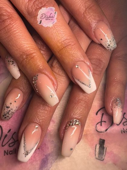 A glamorous set of baby boomer nails with silver glitter and rhinestone V-accents.