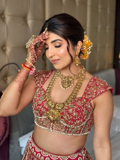 This bride's soft makeup beautifully complements her traditional red lehenga and temple jewellery. This is a perfect example of balancing modern techniques with classic elements.
