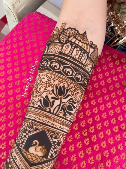 A close-up of a bridal arm, showing bands of swans, elephants, and lotuses.