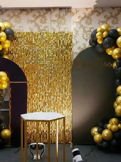 A luxurious black and gold party theme. This setup combines a gold sequin wall with black arched backdrops and dramatic balloon garlands for a high-end, glamorous feel.