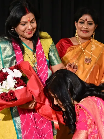A student receives flowers and blessings from a guest. The encouragement from the audience and senior artists means the world to a young debutante.
