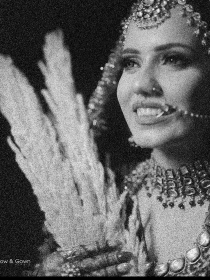 A grainy, artistic black and white bridal portrait. The bride is holding pampas grass, adding a modern, bohemian touch to her traditional look.