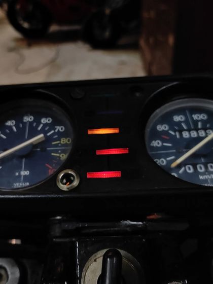 The instrument cluster of the Moto Guzzi glowing, a sign that we're bringing its electronics back to life.