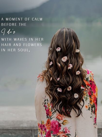 A moment of calm before the I do's. This shot from behind shows the bride's beautiful wavy hair adorned with flowers, overlooking the serene Dal Lake.