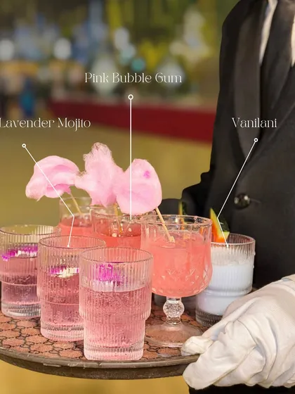 My beverage service is all about creativity and flavour. A server presents a tray of our signature mocktails, including the whimsical Pink Bubble Gum with cotton candy and a floral Lavender Mojito.