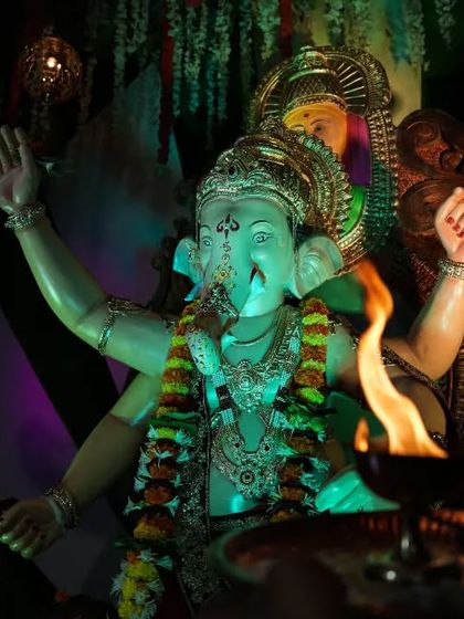 An aarti being performed for the Palmbeach Cha Vighnaharta, with the sacred flame illuminating the idol.
