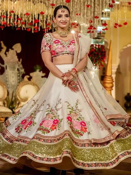 A beautiful bride twirls in a floral embroidered white and pink lehenga. This outfit is a fresh and modern choice for a day wedding or Anand Karaj ceremony, combining traditional grace with a light, celebratory feel.