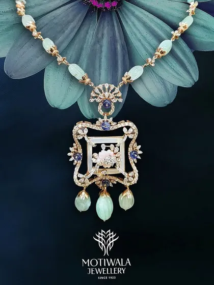 An artistic presentation of a traditional pendant necklace with light green gemstones and Polki diamonds, set against a flower.