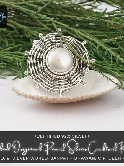 A chunky cocktail ring with a large central pearl set within a coiled, nest-like silver structure. It's a bold, artistic piece for those who love unique designs.
