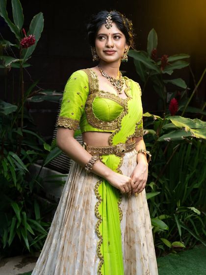 Wrapped in elegance, this half saree features a light gold tissue lehenga paired with a vibrant lime green princess katori blouse. The entire ensemble, including the dupatta, is finished with intricate handwork for a look of traditional grace.