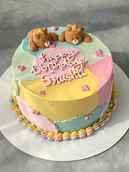 A cute and colorful birthday cake with a pastel patchwork design. It's topped with two adorable teddy bears sculpted from whipped cream, a technique that requires a lot of patience but gives a lovely result.