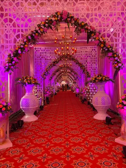 A closer view of the traditional entrance, highlighting the floral arch and the large decorative vases lining the path.