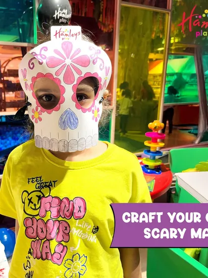 A child wears a scary mask they designed and colored themselves. Our craft stations let every little monster express their unique spooky style.