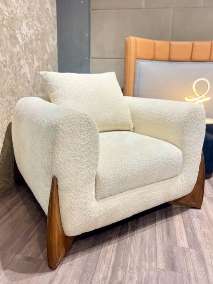 A single armchair in a white bouclé fabric with unique, fin-like wooden legs. This piece is a perfect example of how I blend natural materials with modern, sculptural forms.