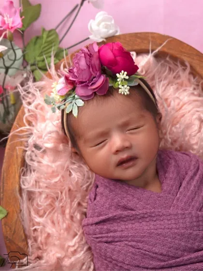 A close-up of a beautiful newborn girl, adorned with a floral headband. The details, from her tiny nose to her soft cheeks, are perfectly captured.