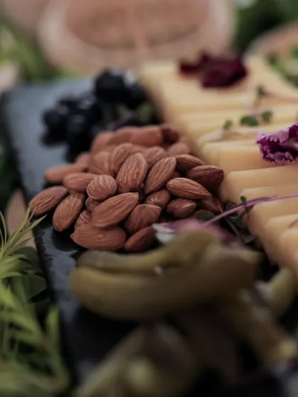 A close-up of a gourmet platter featuring almonds, pickled gherkins, and sliced cheese. We focus on high-quality ingredients and beautiful arrangements in all our food displays.