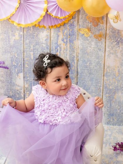 A quiet moment during a first birthday shoot, this baby girl looks so sweet and thoughtful in her pretty purple dress.