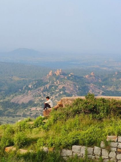 A solo trekker finds a moment of solitude, sitting on the edge of a fort wall.