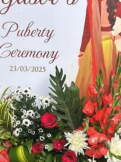 A welcome sign for a Puberty Ceremony, adorned with a fresh and colorful floral arrangement.