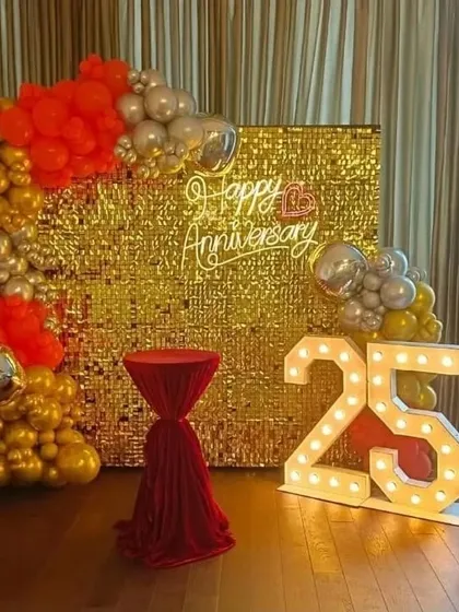 Make a bold statement with a glamorous gold sequin shimmer wall. Paired with a vibrant balloon garland, a custom neon sign, and light-up marquee numbers, this backdrop is designed for unforgettable 25th anniversary parties.