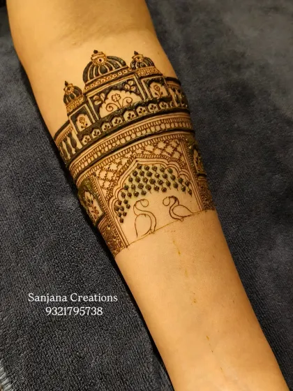 The beginning of a royal bridal arm design, featuring a palace outline with two graceful swans.